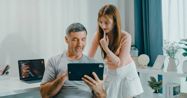 istock Senior father and daughter smile as they use digital tablet together in cozy home, emphasizing family bonding and technology use. Lifestyle family. 2201729428