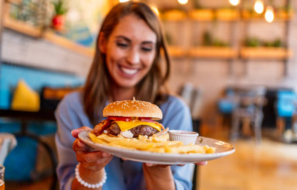 istock Young woman holding a plate with a tasty burger 2201729560