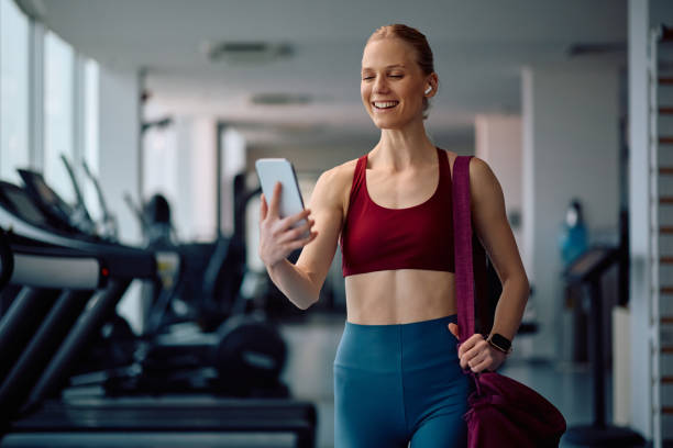 istock Happy sportswoman using mobile phone while working out in a gym. 2201729580