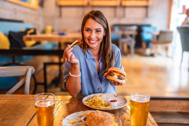 istock Young woman eating burger at the restaurant 2201729945