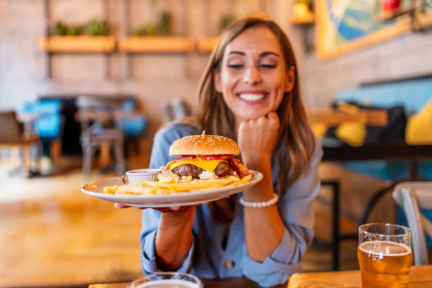 istock Young woman holding a plate with a tasty burger 2201730032