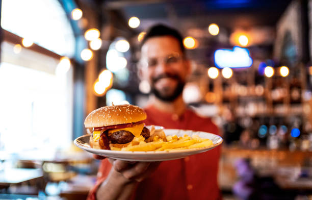 istock Happy man holding a plate with a tasty burger 2201730140