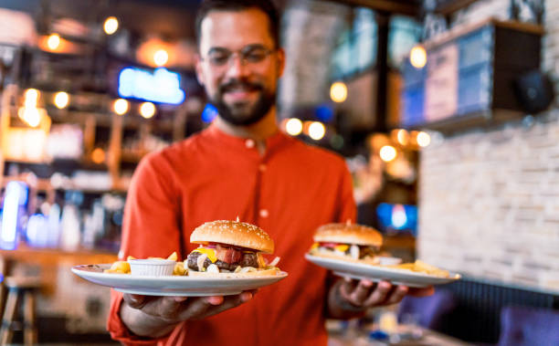 istock Young man holding plates with tasty burgers 2201730246