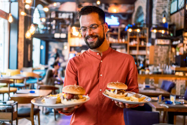 istock Young man holding plates with tasty burgers 2201730292