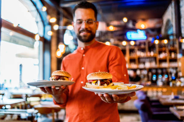 istock Young man holding plates with tasty burgers 2201730434