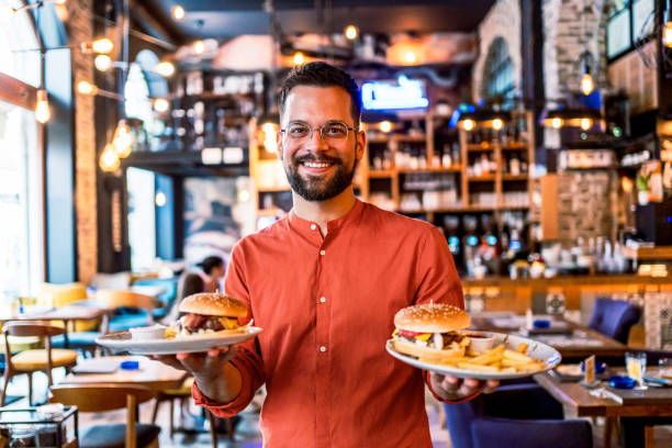istock Young man holding plates with tasty burgers 2201730472