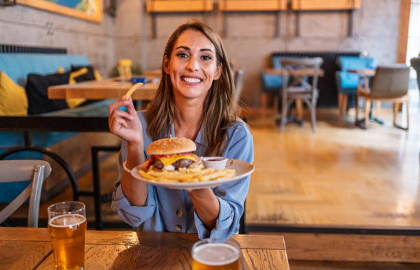 istock Young woman eating burger at the restaurant 2201730624