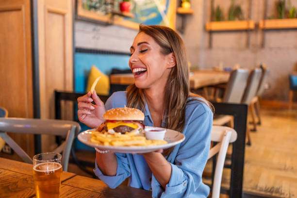 istock Young woman eating burger at the restaurant 2201730639