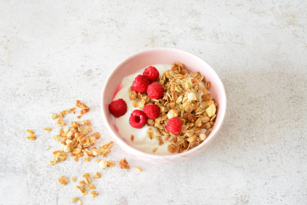 istock Granola with Yogurt and Raspberries in pink bowl top view 2201733925