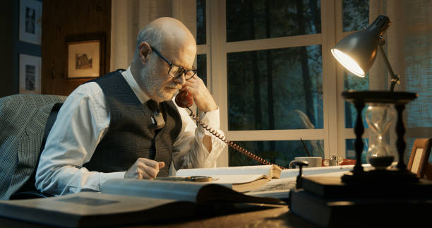 istock Professor sitting at desk and answering phone calls 2201736274