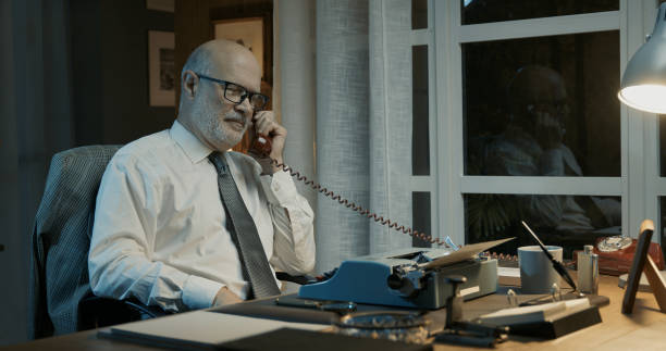 istock Professor sitting at desk and having a phone call 2201737002