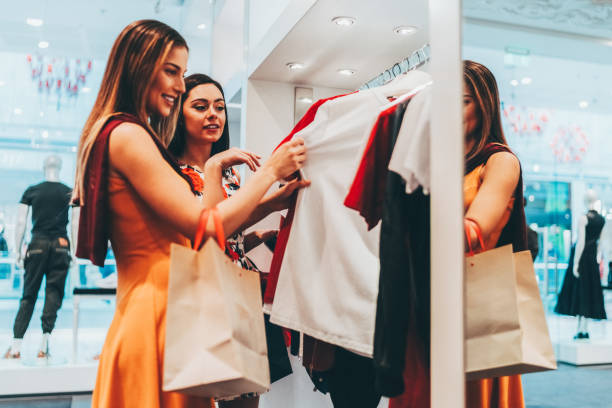 istock Young women in the shopping mall choosing clothes 2201737826