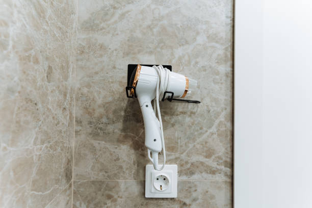 istock A hair dryer is currently hanging securely on a wall right next to an electrical socket, making it conveniently accessible for use whenever it is needed for drying hair or styling 2201737896
