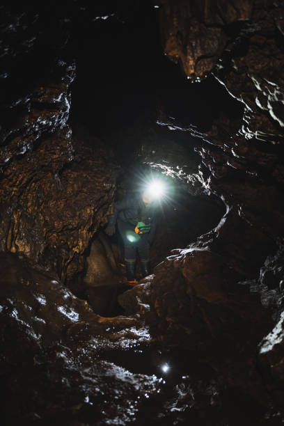 istock A solitary figure is standing inside a dimly lit cave, wearing a bright light on their head to illuminate the surrounding darkness, surrounded by various natural elements 2201737909