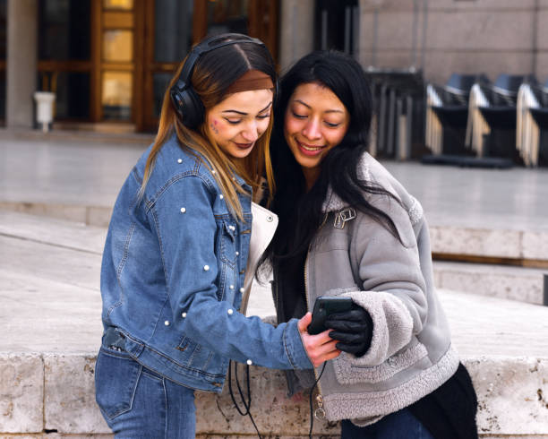 istock Two friends enjoy music together while sharing a moment outdoors in a lively urban setting 2201741723