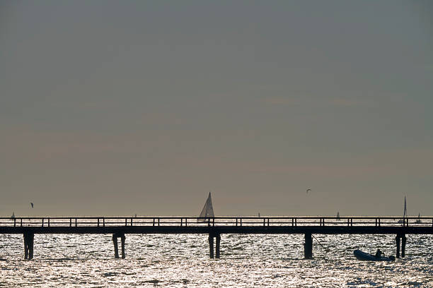 Sunset view of a pier on the Kitsilano shoreline looking out towards West Vancouver and English Bay, British Columbia