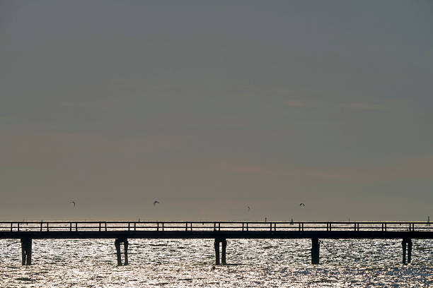 Sunset view of a pier on the Kitsilano shoreline looking out towards West Vancouver and English Bay, British Columbia