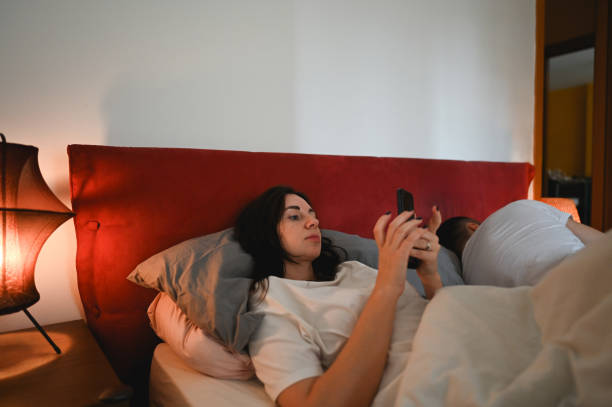 istock woman using mobile phone in bedroom. 2201746586