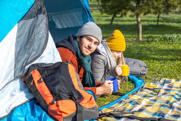 istock Couple camping and drinking hot drinks in front of tent 2201747237