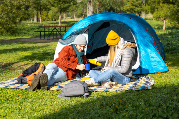 istock Couple enjoying hot drinks in front of tent during camping trip 2201747240