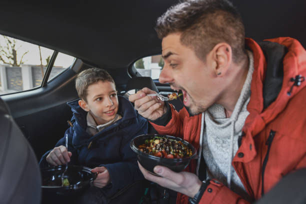 istock Smiling Father and Son Eating Nutritious Meal in the Car 2201747849