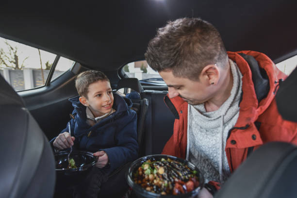 Smiling Father and Son Sharing Nutritious Meal Inside the Car