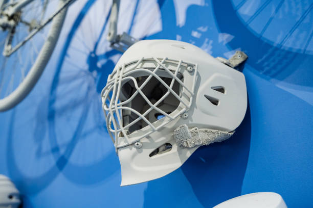 A white hockey goalie mask is beautifully mounted on a blue wall, complemented by striking silhouettes of bicycles, showcasing sports themes