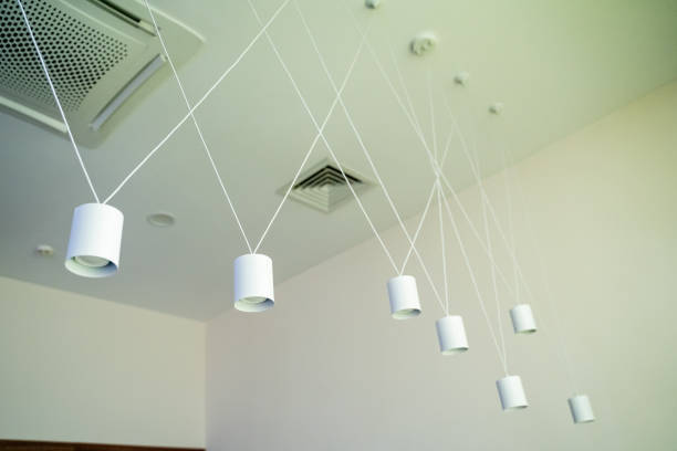 A row of white pendant lights hanging from the ceiling in a room. High quality