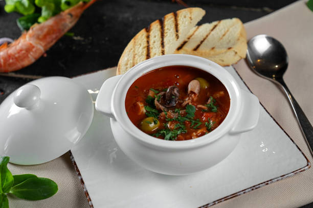istock menu for a restaurant, seafood tomato soup with olives in a pot, beautiful presentation and serving on a black background 2201748505