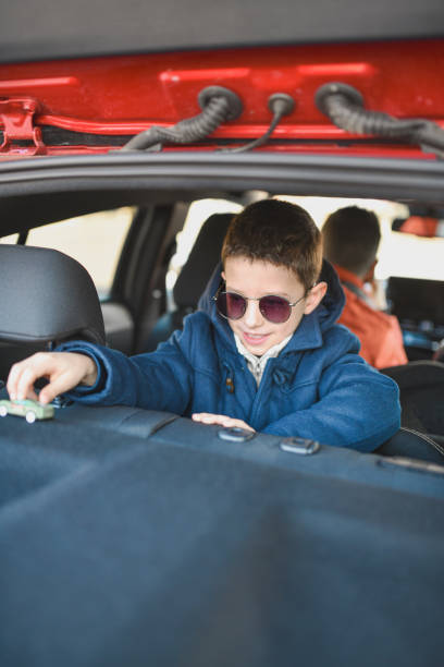 istock Cute Boy Entertaining Himself Playing With Car Toy While His Father is Driving 2201748751