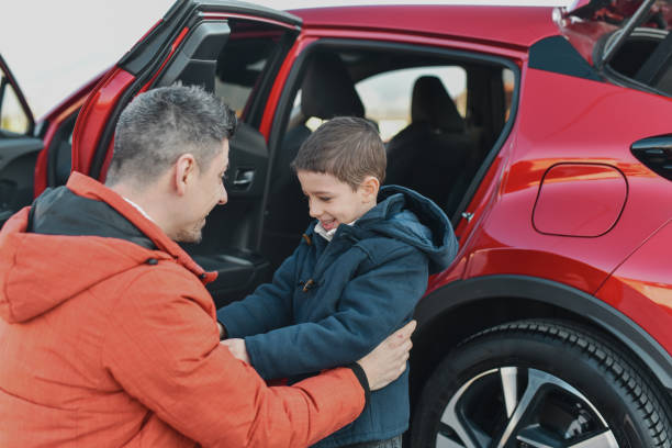 istock Single Father Bonding With Cute Son Embracing Him in Front of Modern Red Car 2201749079