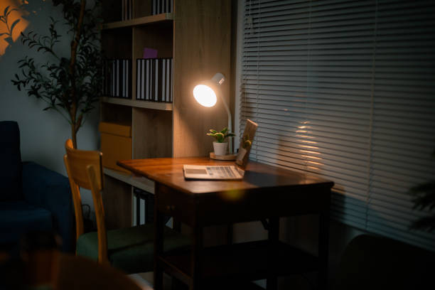 Illuminating a cozy home office desk at night, a laptop rests beside a desk lamp, creating a warm and inviting workspace perfect for working, studying, or relaxing