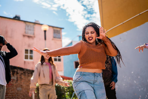istock Young woman dancing with friends outdoors 2201760942