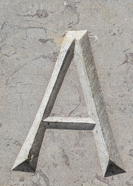 Close-up of three-dimensional sand alphabet on white background.