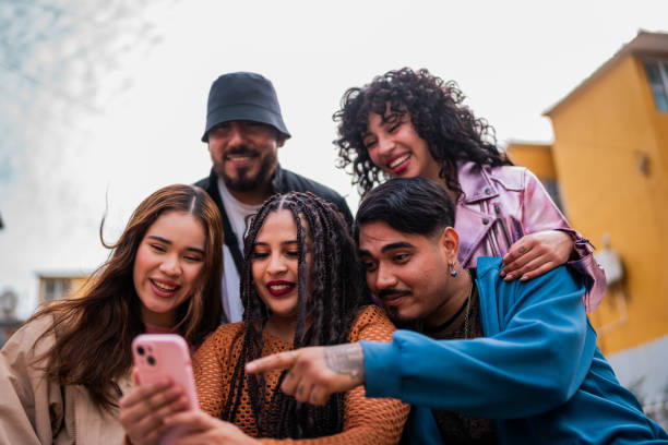 istock Young friends using mobile phone and talking outdoors 2201761932