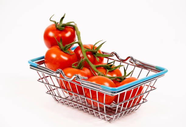 A small metallic shopping basket is filled with vibrant red tomatoes still on the vine, showcasing their freshness and appeal for culinary use.