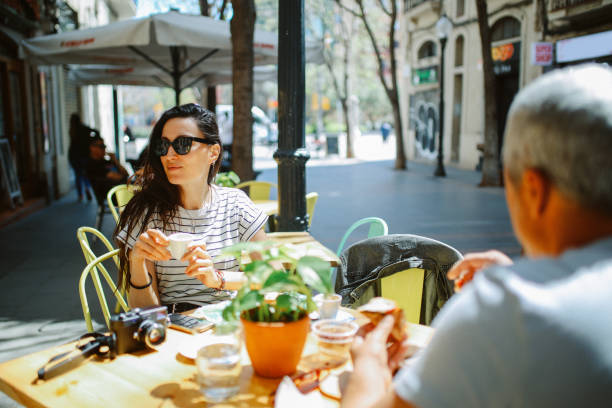 Friends sitting in a cafe in Barcelona, drinking coffee, enjoying a sunny day. They are just tourists on a city break or locals spending a relaxed weekend.