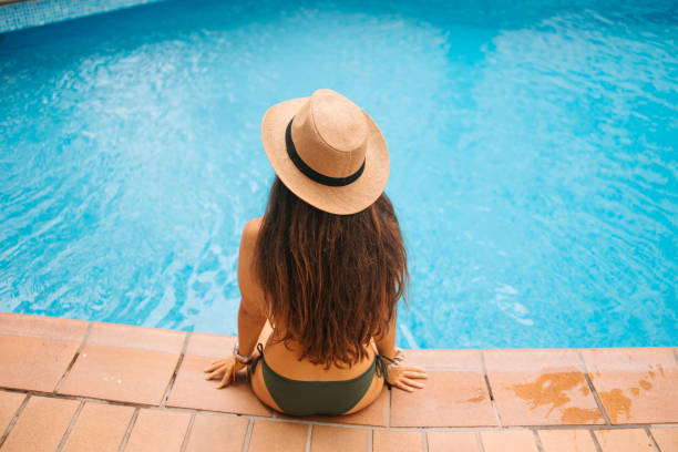istock Woman sitting by the pool 2201764105