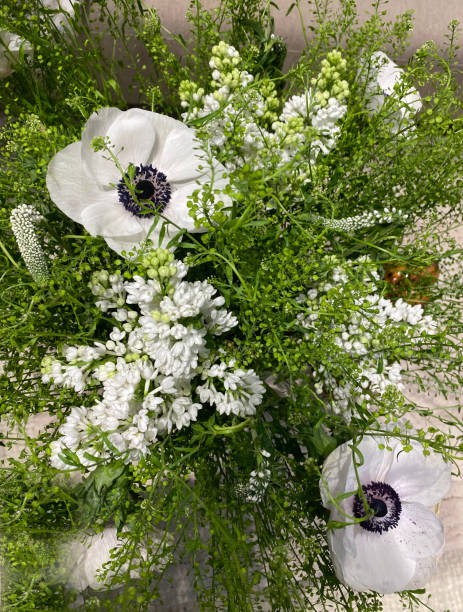 White anemones (Anemona coronaria) with a black center and white lilac in a spring bouquet.