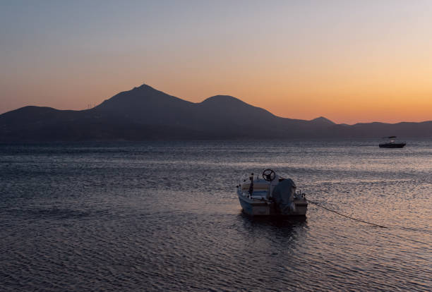 Relaxing sea landscape with boats and calm Mediterranean sea with colorful sunset.