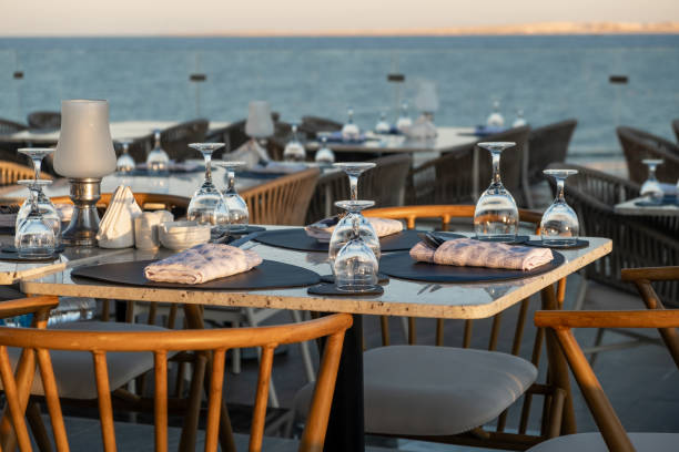 istock Elegant seaside dining setup with glassware, overlooking the ocean at sunset. 2201780338