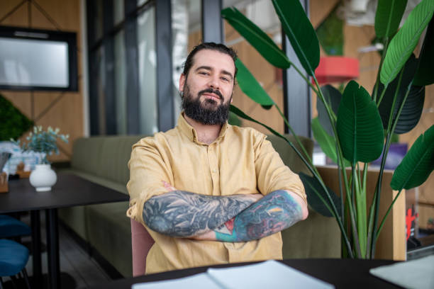 Portrait of young bearded, tattooed man in cafe. stock photo