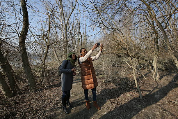 istock Two young women taking pictures in a park during winter 2201784576