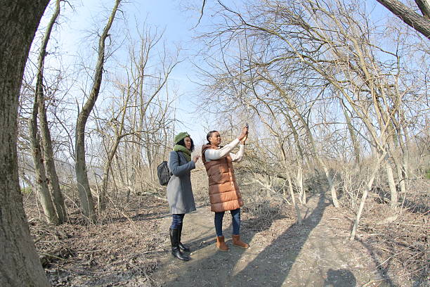 istock Two young women taking pictures in bare forest 2201784872