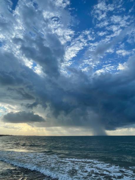 istock A storm clouds and rain in the sea with clouds and blue sky view from a beach 2201791455