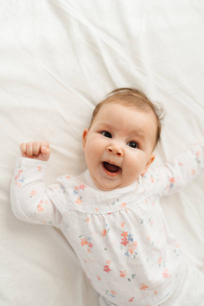 istock Adorable Baby Lying on a Soft White Bed 2201791546