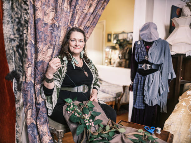Mature woman costume designer working in her home studio. She is sewing new creation. Dressed in casual clothes, designed by her. Interior of creative studio at home in Hamilton, Canada.