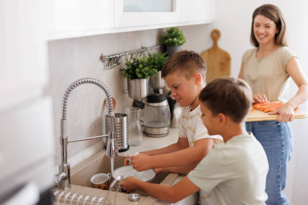 istock Children washing dishes while mother prepares food in kitchen 2201793470