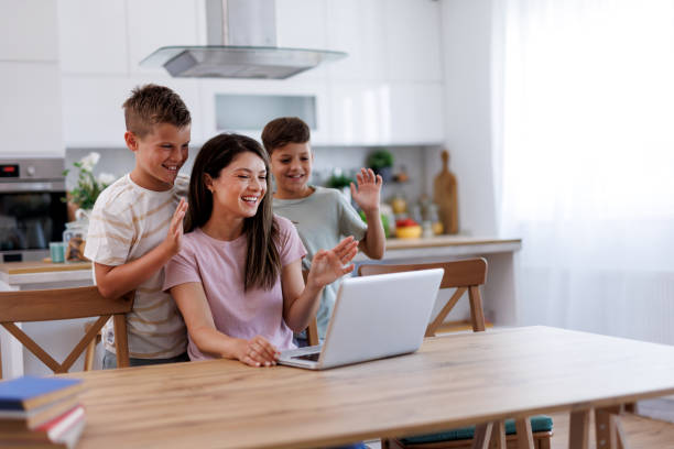 istock Happy family waving at someone during a video call in kitchen 2201793509
