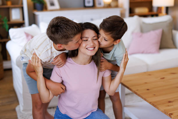istock Two sons kissing their mother on the cheeks at home 2201793567